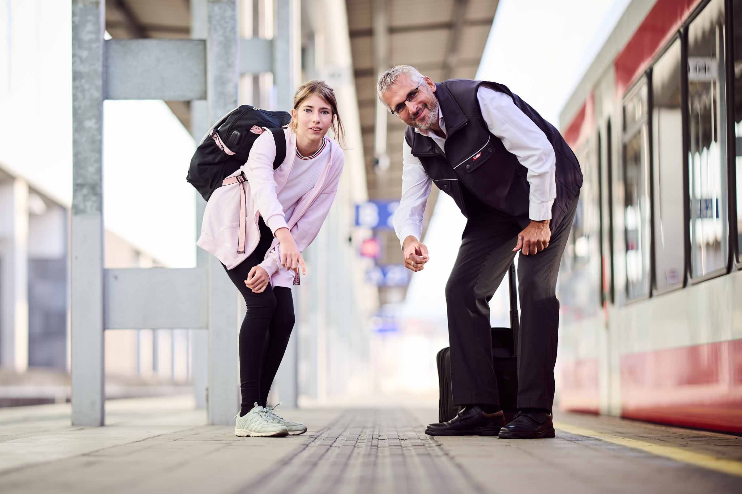 Ein junger Fahrgast und ein Mitarbeiter von ÖBB-Operative Services deuten auf das Blindenleitsystem am Bahnsteig.
